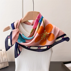 Détail d'un foulard en soie avec fleurs oranges et bordure bleu marine élégante