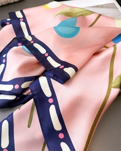 Gros plan d'un foulard en soie avec imprimés floraux roses et bordures géométriques bleues