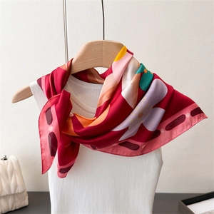 Détail d'un élégant foulard en soie rouge à motif floral sur un cintre en bois