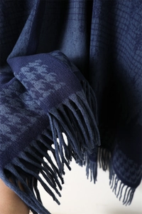 Detail of navy blue houndstooth scarf showing soft cashmere-like texture and fringed edges