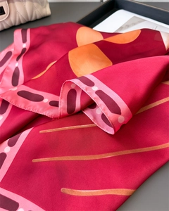 Gros plan d'un foulard en soie aux imprimés floraux rouges et orangés, texture lisse