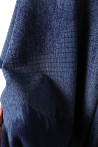 Detailed macro view of the dark blue herringbone fabric texture with fringed shawl details