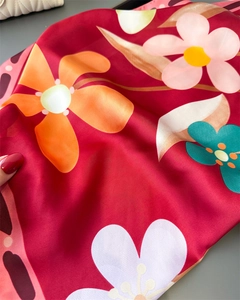 Détail du motif floral coloré sur foulard en satin rouge soyeux avec texture lisse