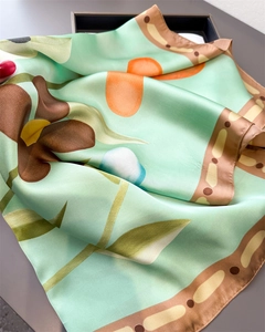 Détail d'un foulard en soie à fleurs vert menthe avec une texture satinée élégante