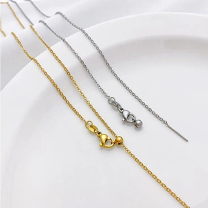 Adjustable stainless steel cross chain necklace set in gold and silver finish on ceramic plate