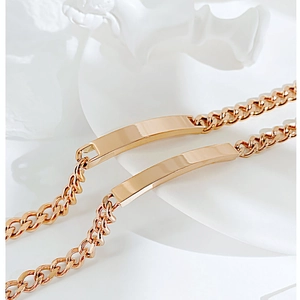 Macro view of gold-plated Cuban link bracelets with polished bar on a white tray