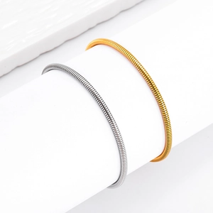 Elegante goldene und silberne Schlangenknochen-Armbänder aus Edelstahl auf Weiß
