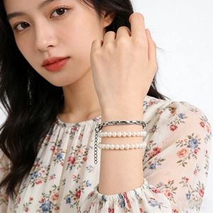 Close-up of triple-layered bracelet set featuring white pearls and flat stainless steel chain