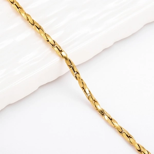 Macro detail of 18K gold-plated oval link chain bracelet on a minimalist white ceramic tray