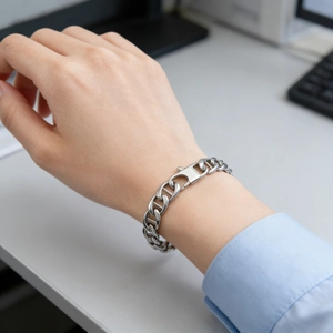 Silver stainless steel curb link bracelet for men shown on wrist in a daily office setting