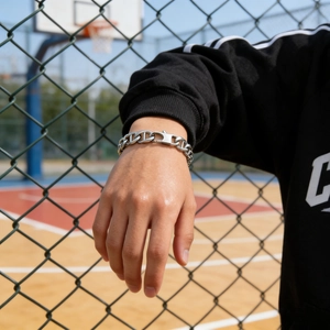 Close-up of industrial silver anchor link bracelet worn on wrist in a street setting
