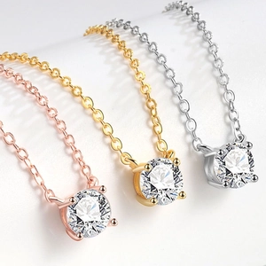 Détail de trois colliers en acier inoxydable or, or rose et argent avec zircon rond de 7 mm