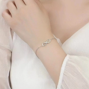 Gros plan du bracelet infini avec diamants sur un poignet avec un fond en tulle élégant