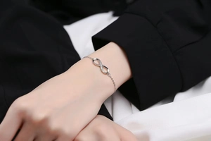 Gros plan du bracelet symbole infini avec cristaux porté sur un poignet femme