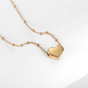 Detailed macro shot of 18k gold heart pendant featuring a polished finish on bead chain