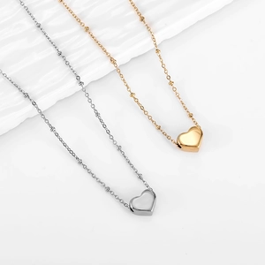 Close-up of 18k gold and silver 3D heart pendants on delicate beaded chain necklaces