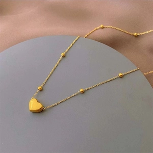 Detailed view of 18k gold heart pendant on a delicate beaded chain with a glossy finish