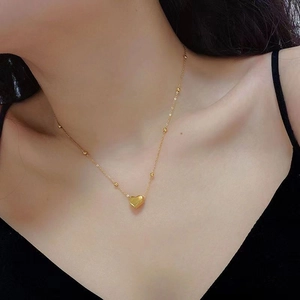 Detailed view of 18k gold heart pendant necklace with bead chain on woman neck