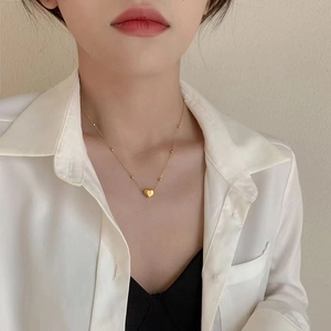Macro view of 18k gold heart pendant necklace with beaded chain on female model