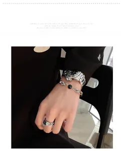 Detail view of silver chain bracelet with black bead and wide metal ring for men