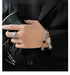Close-up of cool men's obsidian beaded bracelet with cross and chunky industrial ring