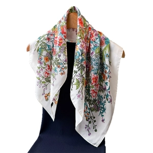 Elegante foulard in seta bianca con stampa floreale vivace su appendiabiti in legno