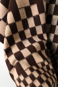 Detail of soft brown and beige checkerboard knit fabric with premium texture and fringe