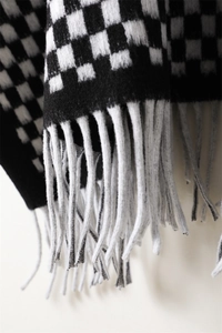 Close-up of black and white checkerboard scarf featuring long fringe and soft texture