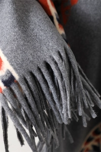 Close-up of grey tassel fringe and ethnic geometric patterns on a warm winter shawl