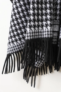 Close-up of black and white houndstooth wool-like fabric with elegant fringe tassels
