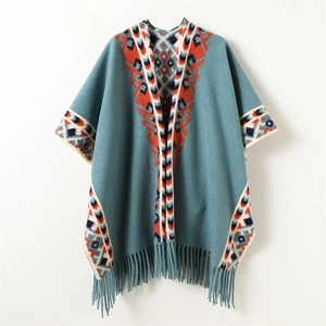 Detail view of ethnic geometric jacquard pattern and long fringes on a blue knit poncho
