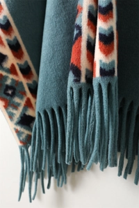 Detailed macro shot of blue cashmere shawl featuring ethnic jacquard patterns and soft tassels