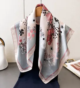 Detail view of a floral silk scarf with daisy patterns hanging on a wooden hanger