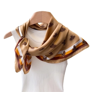 Vintage silk scarf with bee patterns styled on a white vest and wooden hanger