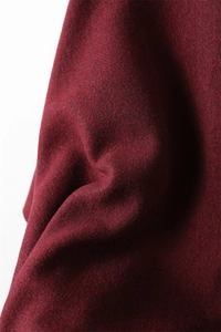 Gros plan sur le tissu bordeaux aspect cachemire montrant la texture douce et l'épaisseur