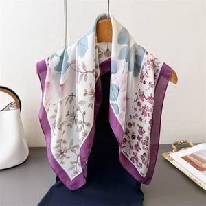 Elegant floral silk scarf in purple and blue, draped on a hanger with lifestyle props