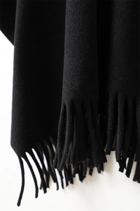Gros plan sur la texture douce imitation cachemire et les franges délicates du châle noir