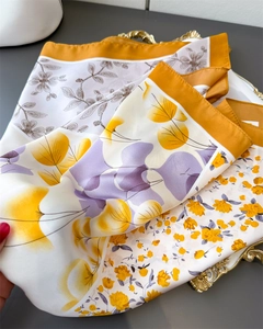 Detailed view of floral silk scarf with yellow and purple patterns on a golden tray
