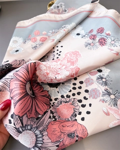 Detailed close-up of retro floral print silk scarf with fine rolled edges and satin texture