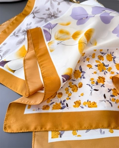 Detail view of floral silk-feel scarf with ginger yellow borders and lavender patterns
