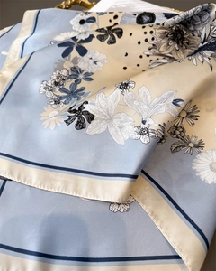 Detailed view of floral silk scarf with lily and daisy prints in blue and beige