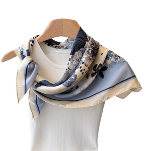 Floral print silk-like scarf draped on a white vest with a wooden hanger
