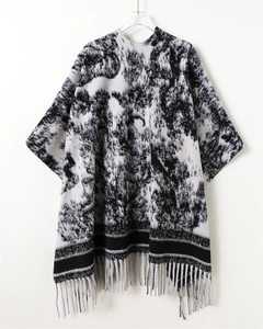 Detail of knit shawl featuring abstract ink wash pattern and delicate grey fringe tassels