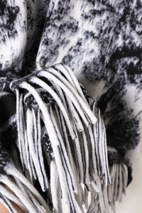 Detailed close-up of ink wash pattern cashmere-like shawl with thick bicolor tassels