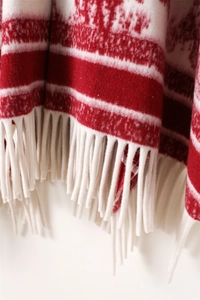Detail of red and white striped knit shawl featuring soft cashmere-like texture and long white tassels