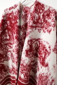 Detail of red and white jacquard knit shawl showing soft texture and striped hem
