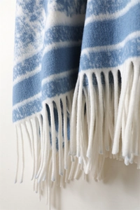 Detailed view of blue and white striped shawl with thick soft white fringe tassels
