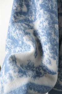 Close-up of soft faux cashmere fabric with blue ink wash art texture and fuzzy finish