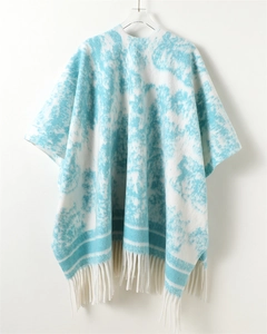 Close-up of knit shawl detailing ink-wash texture and delicate white fringe hem