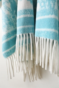 Close-up of blue and white striped cashmere-like knit shawl with elegant white tassels